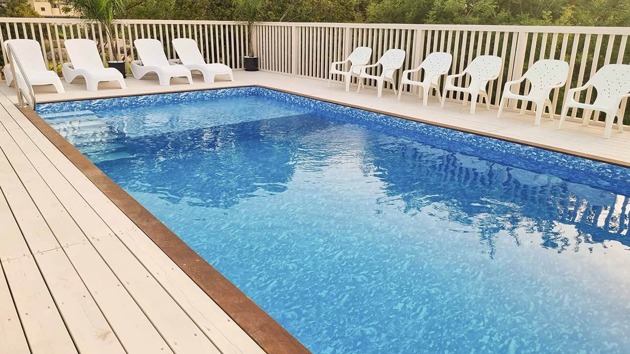 בריכת שחייה פרטית עם משטח עץ ומרפסת נוחה, מושלמת לבילוי.
